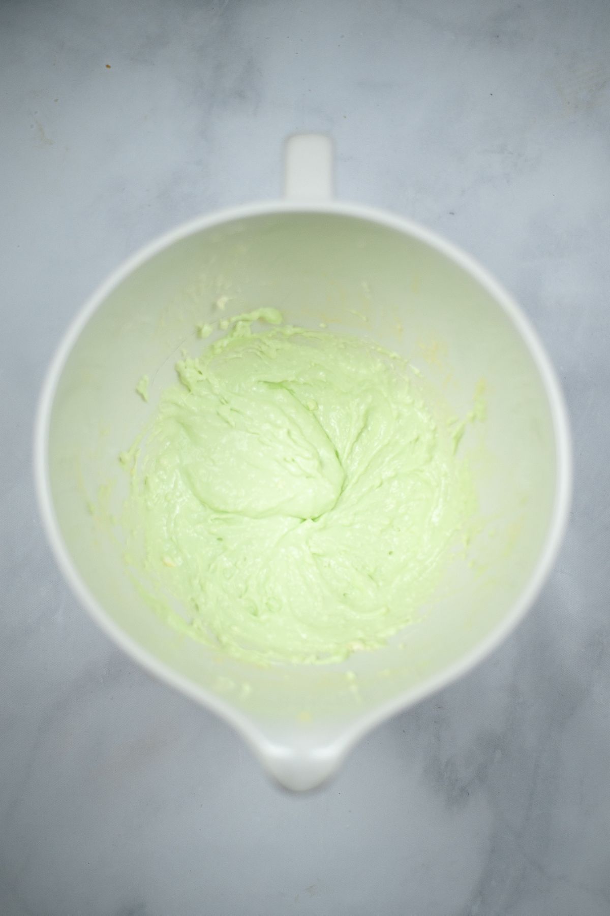 cream cheese, sugar, egg, mint extract and food coloring combined in a mixing bowl.