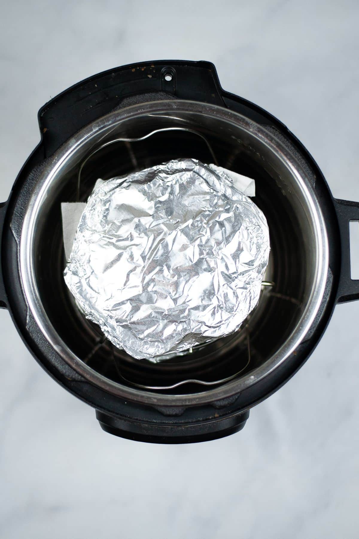 Egg mold covered with foil on a tall trivet inside the instant pot.