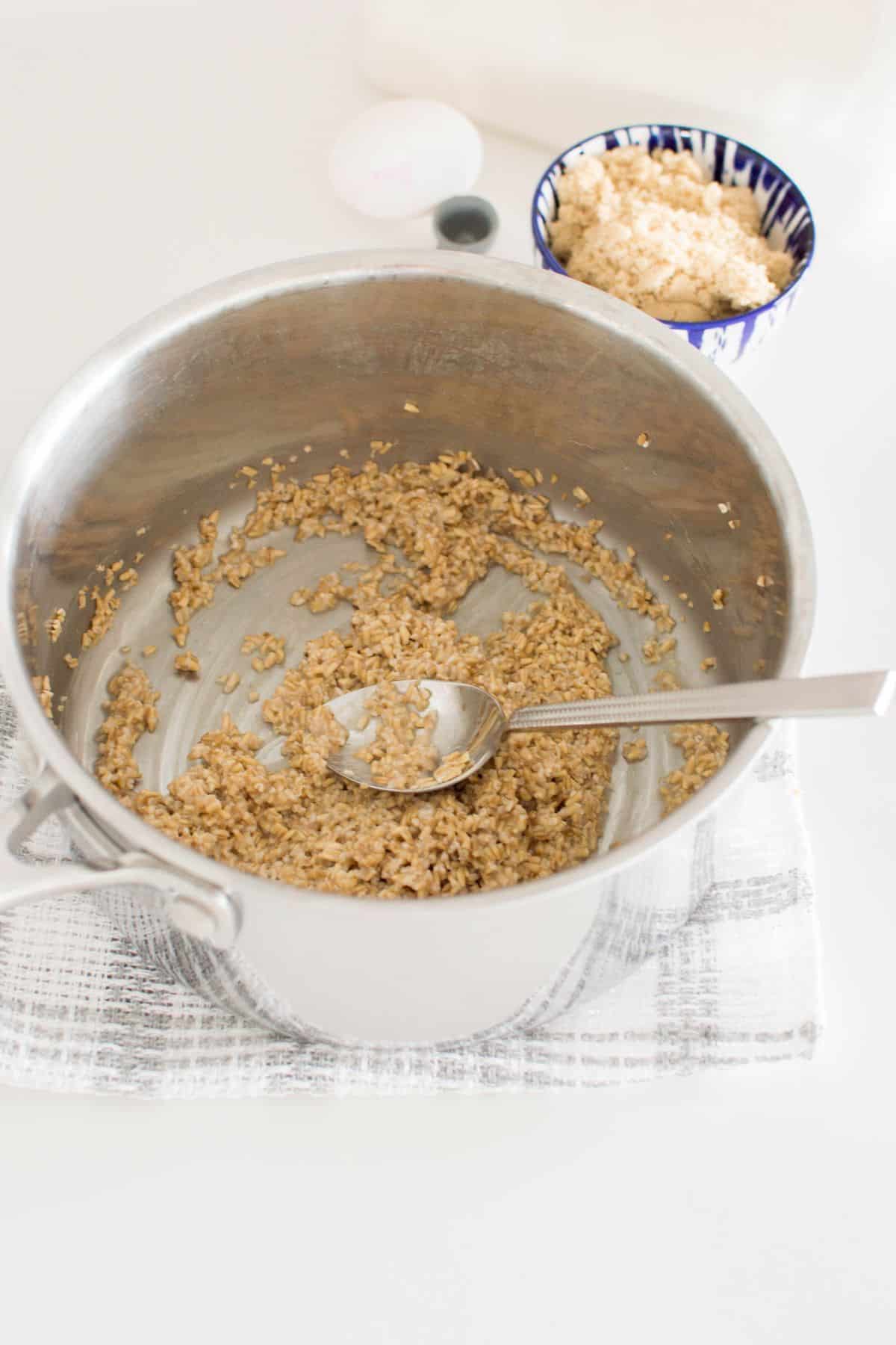 oats and water in a saucepan, with a spoon.