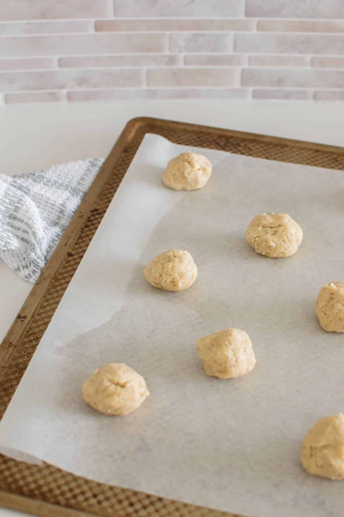 cookie dough rolled into balls and placed on a baking pan.
