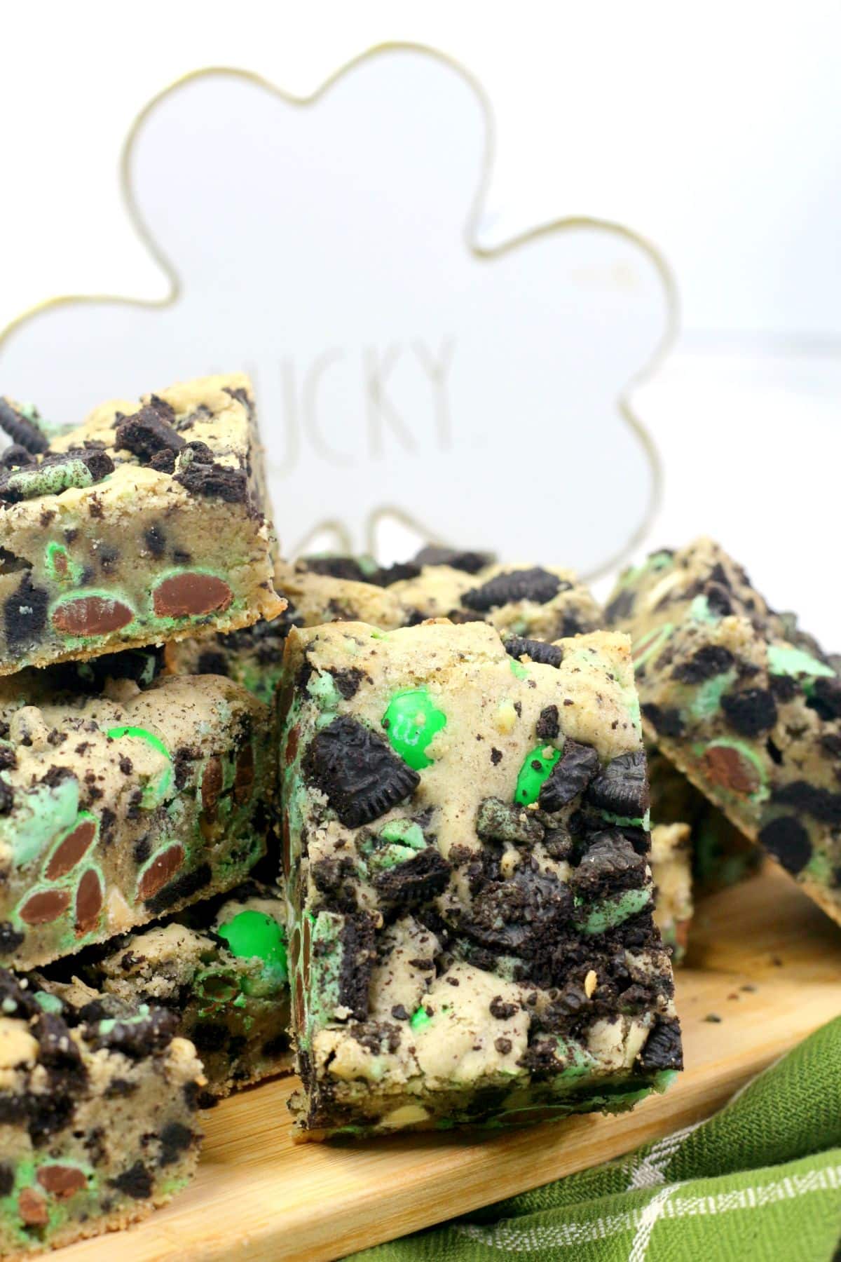 Cookie bars sit on a wooden board, surrounded by green cloth.