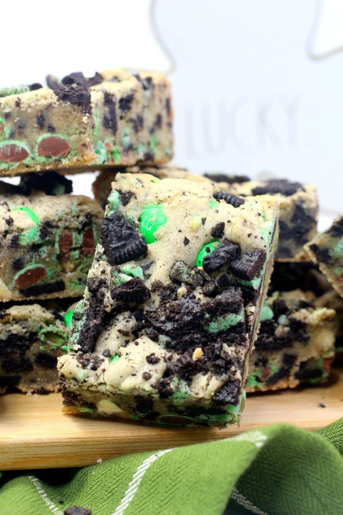Cookie bars sit on a wooden board, surrounded by a green cloth.