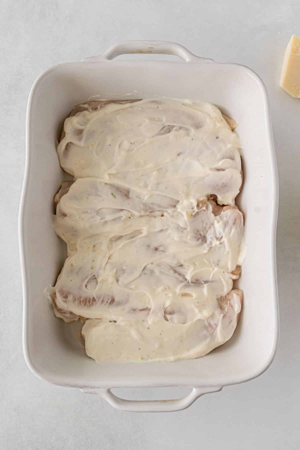 chicken in a baking dish topped with mayo mixture.