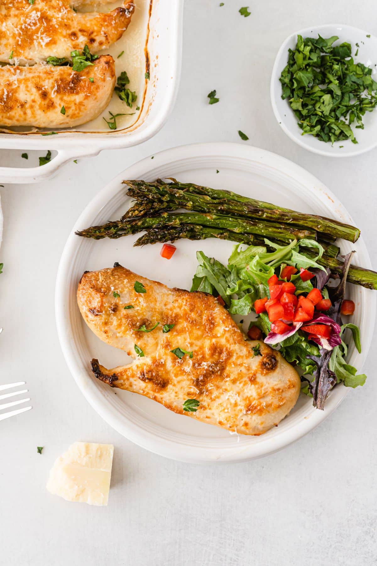 Mayo Parmesan Chicken on a serving plate with asparagus and salad on the side.