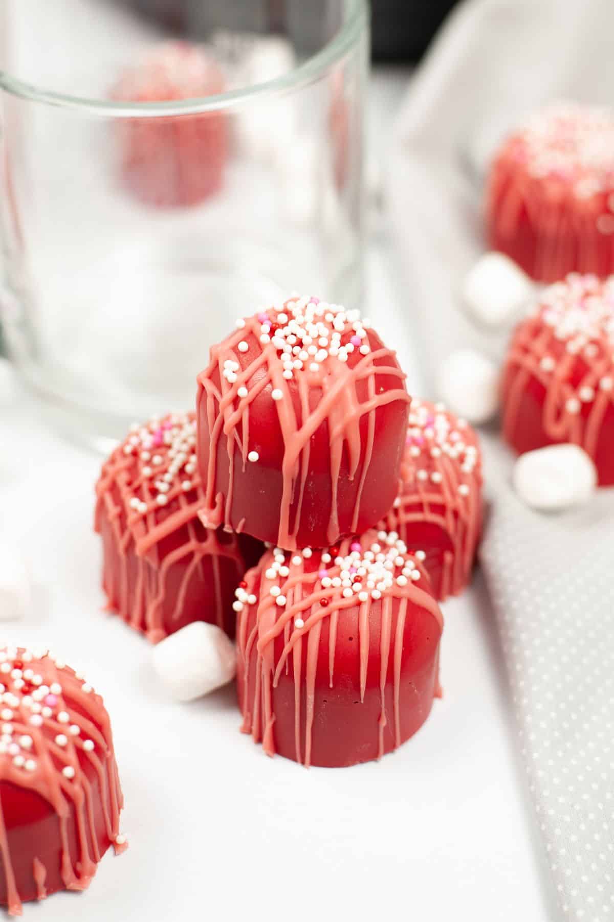 Valentine Cocoa Bombs with marshmallows and a mug on the side.