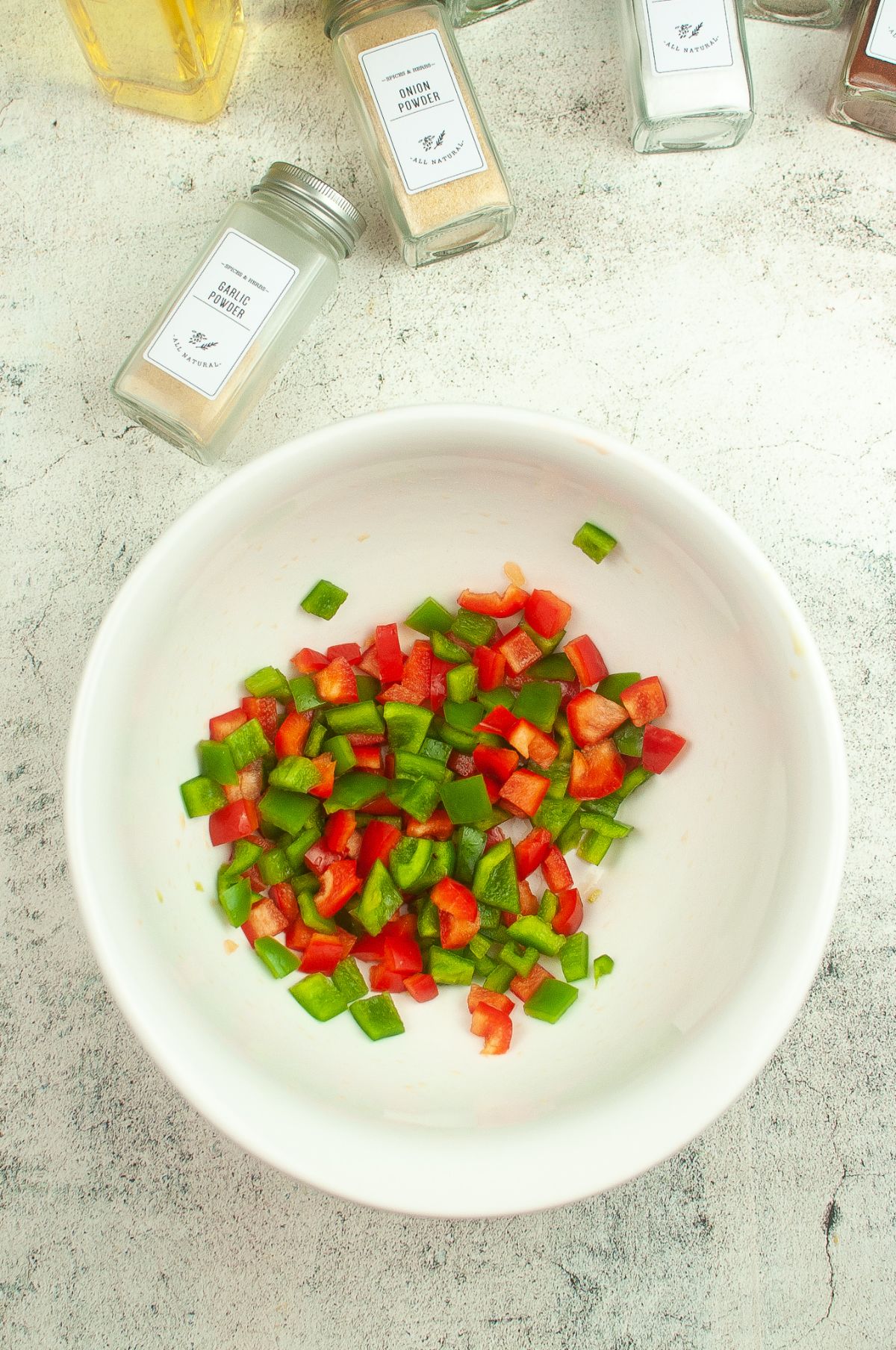 chopped peppers in a small bowl with  spices and oil on the side.