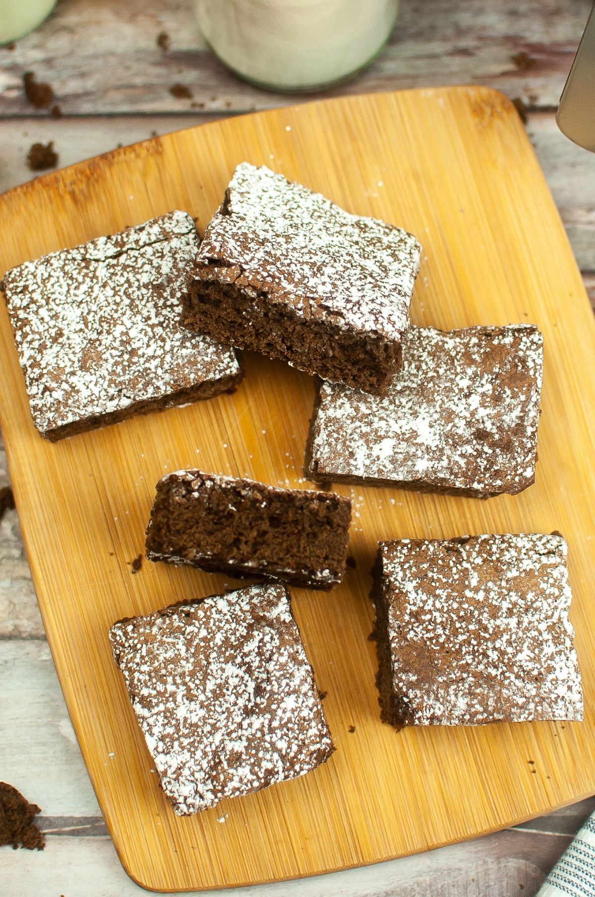 A brownie is cut into squares on a wooden chopping board.