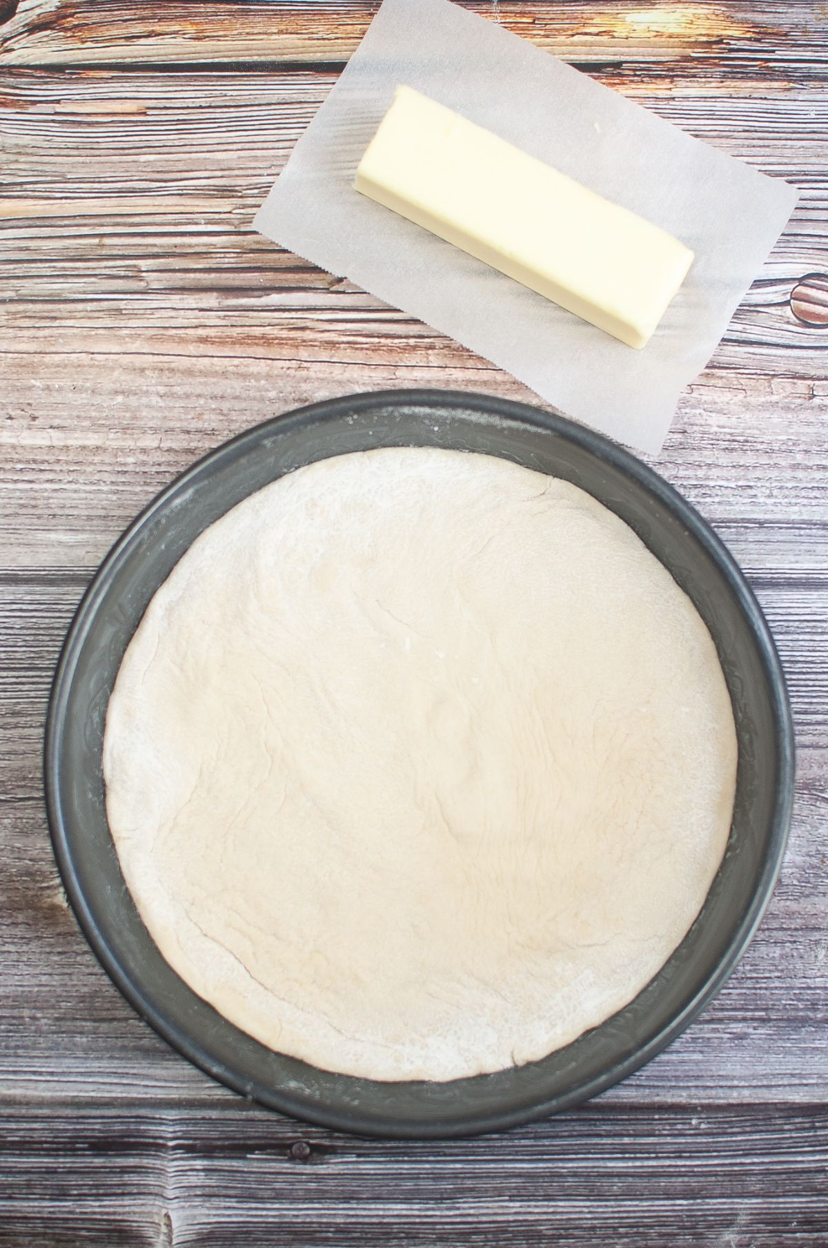 Rolled out dough on a pan with butter on the side.