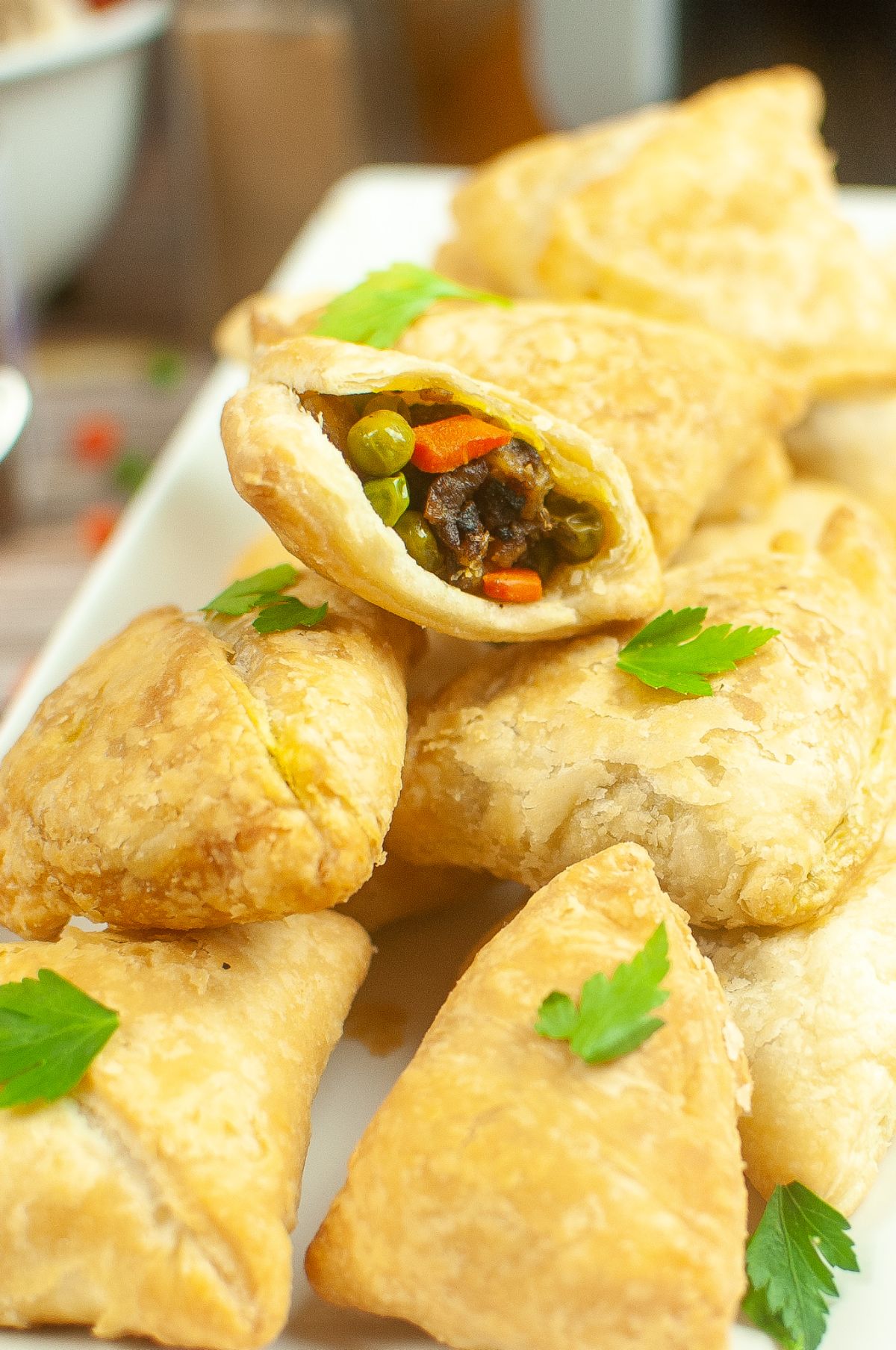 Air Fryer Samosas with a single open bite on a serving plate., garnished with parsley.
