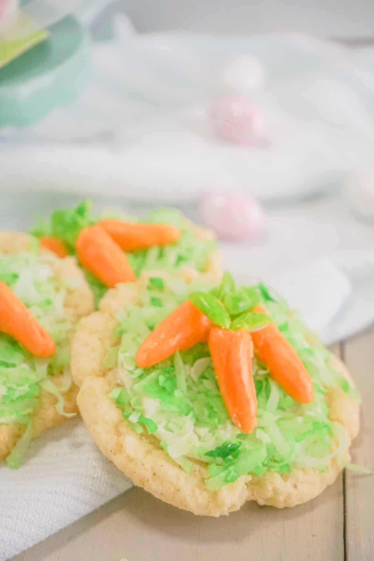 Carrot Sugar Cookies on a white cloth. easter egg candies on the side.