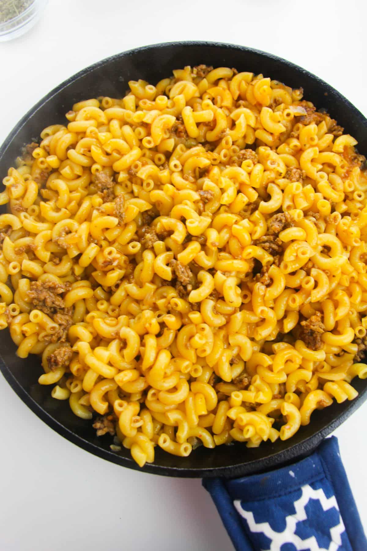 In a large skillet, ground beef, onion, tomato pasta, broth, pasta, are  combined.