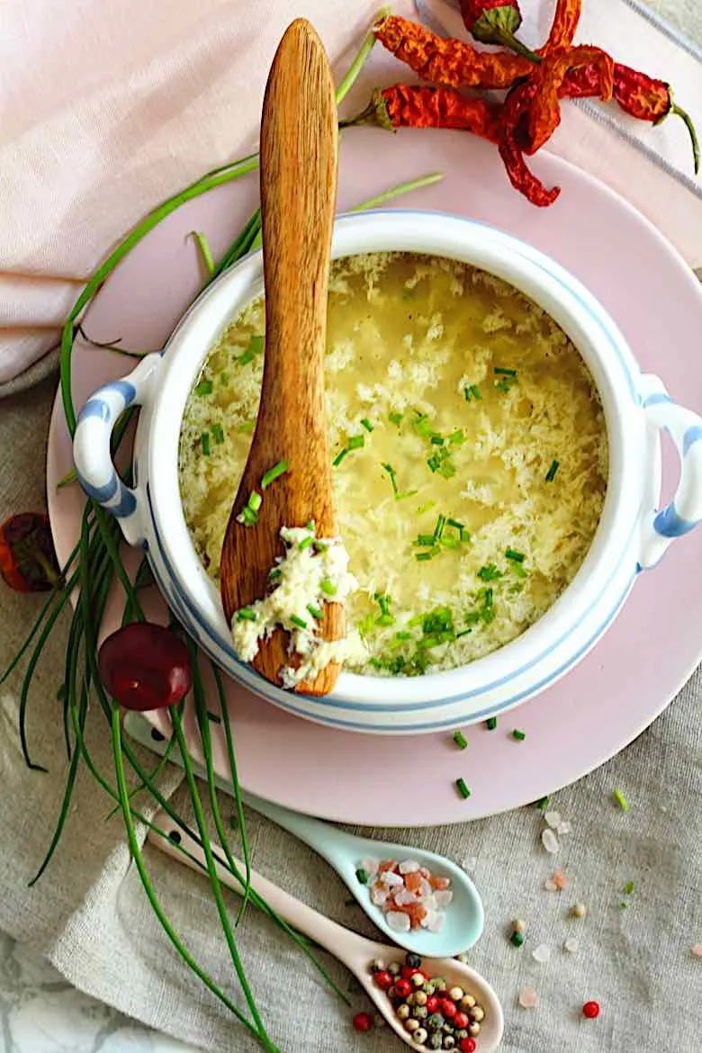 Keto Egg Drop Soup in a serving bowl, garnished with green onion and a wooden spoon on top. 