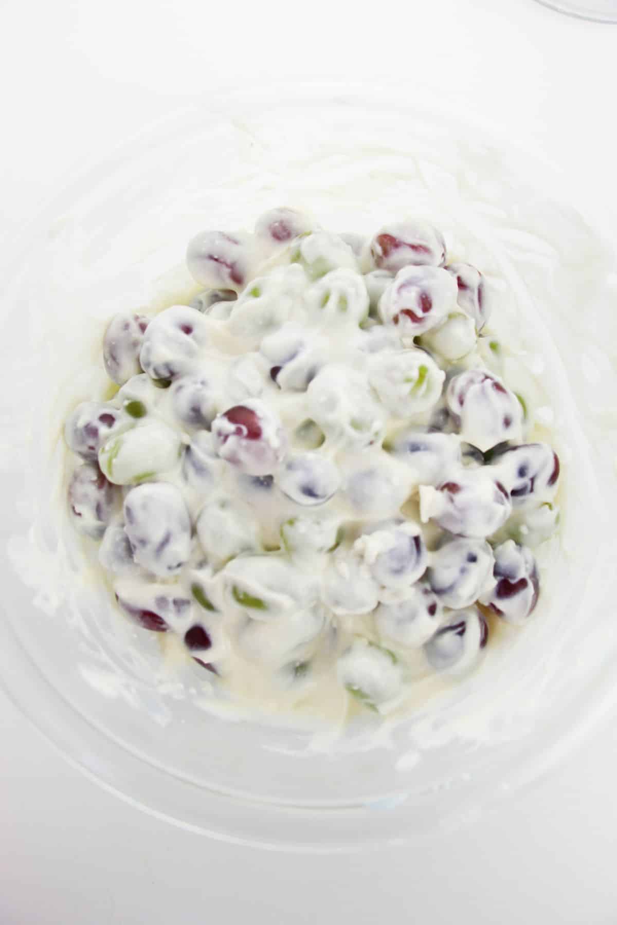 Grapes are added to the cream mixture in a large bowl.