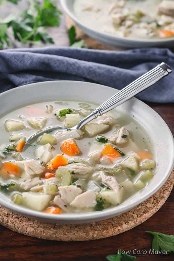 Low-Carb Chicken Soup in a serving bowl with serving spoon in it garnished with parsley. 
