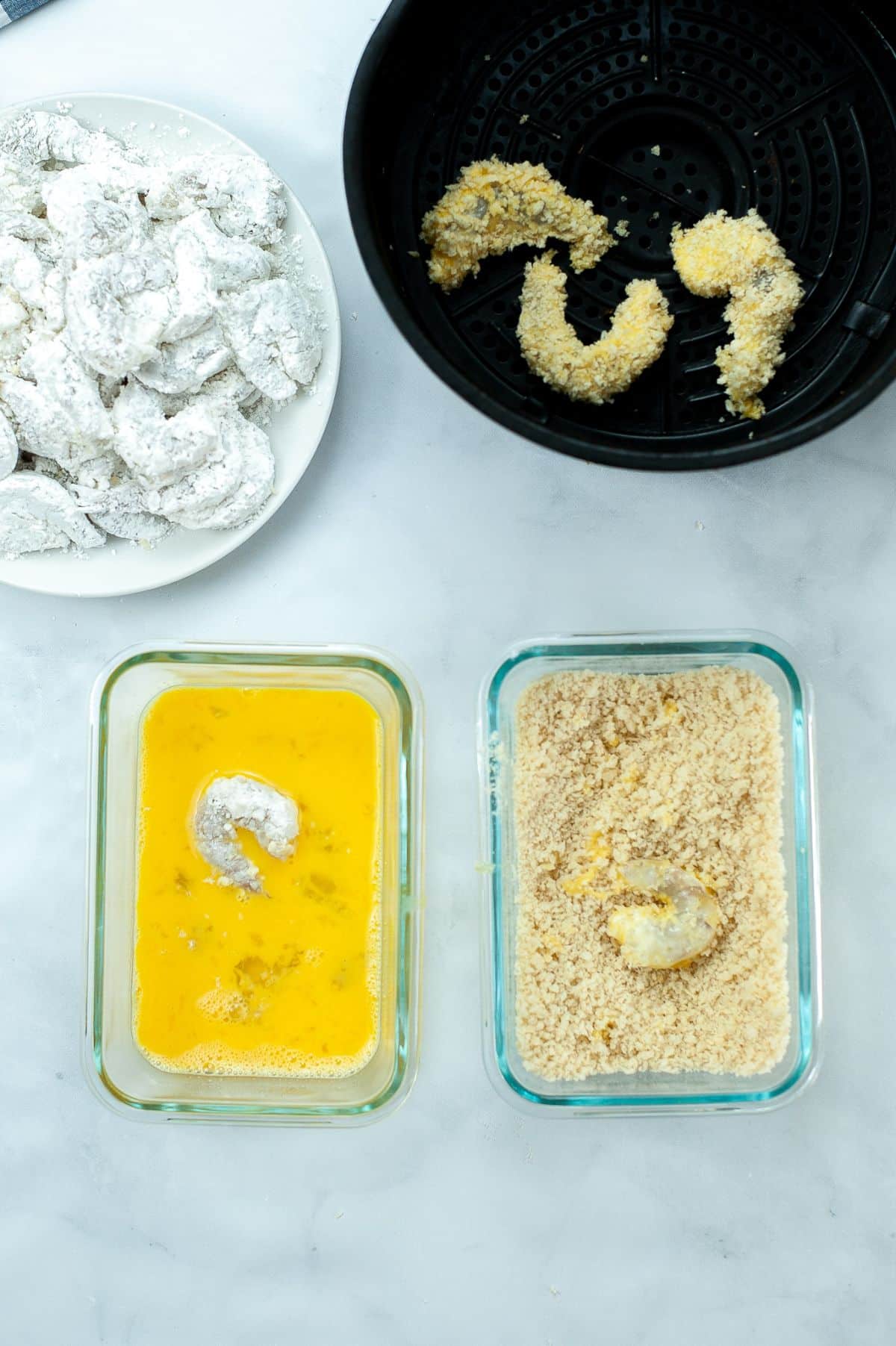 shrimp being dipped in egg, panko crumbs and cornstarch, and placed in an air fryer