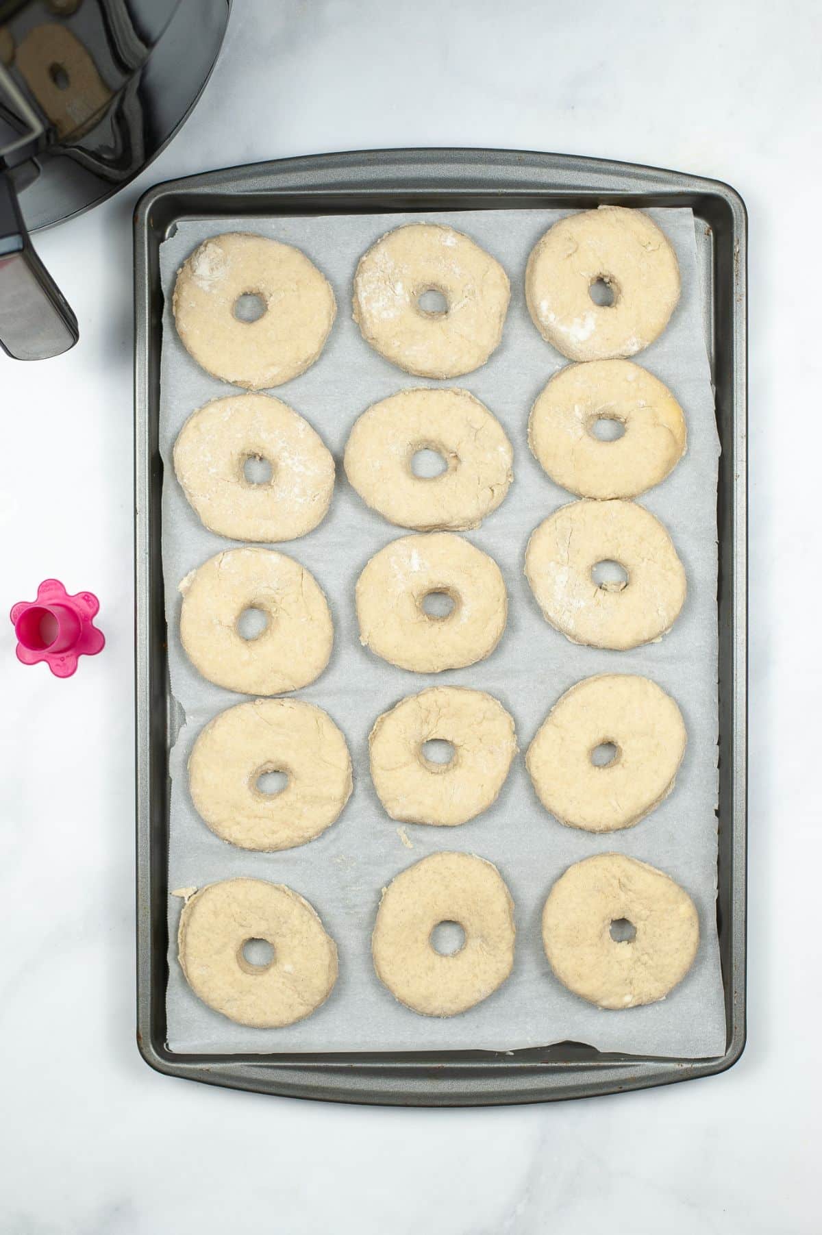 donuts on parchment paper on a baking sheet next to an air fryer