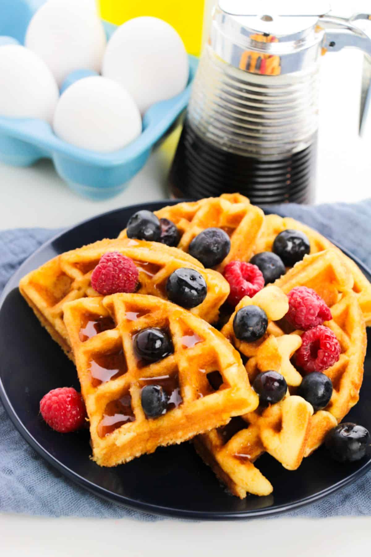 Cake Mix Waffles on a serving plate, garnished with maple syrup and berries. 