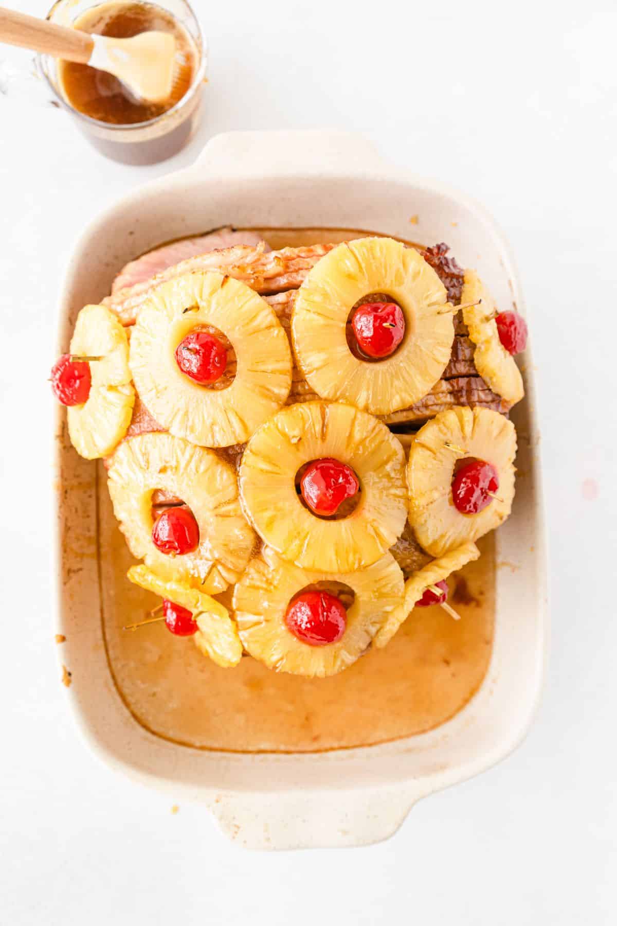 Baked ham with cherries and pineapples in a baking dish. marinade and brush on the side.