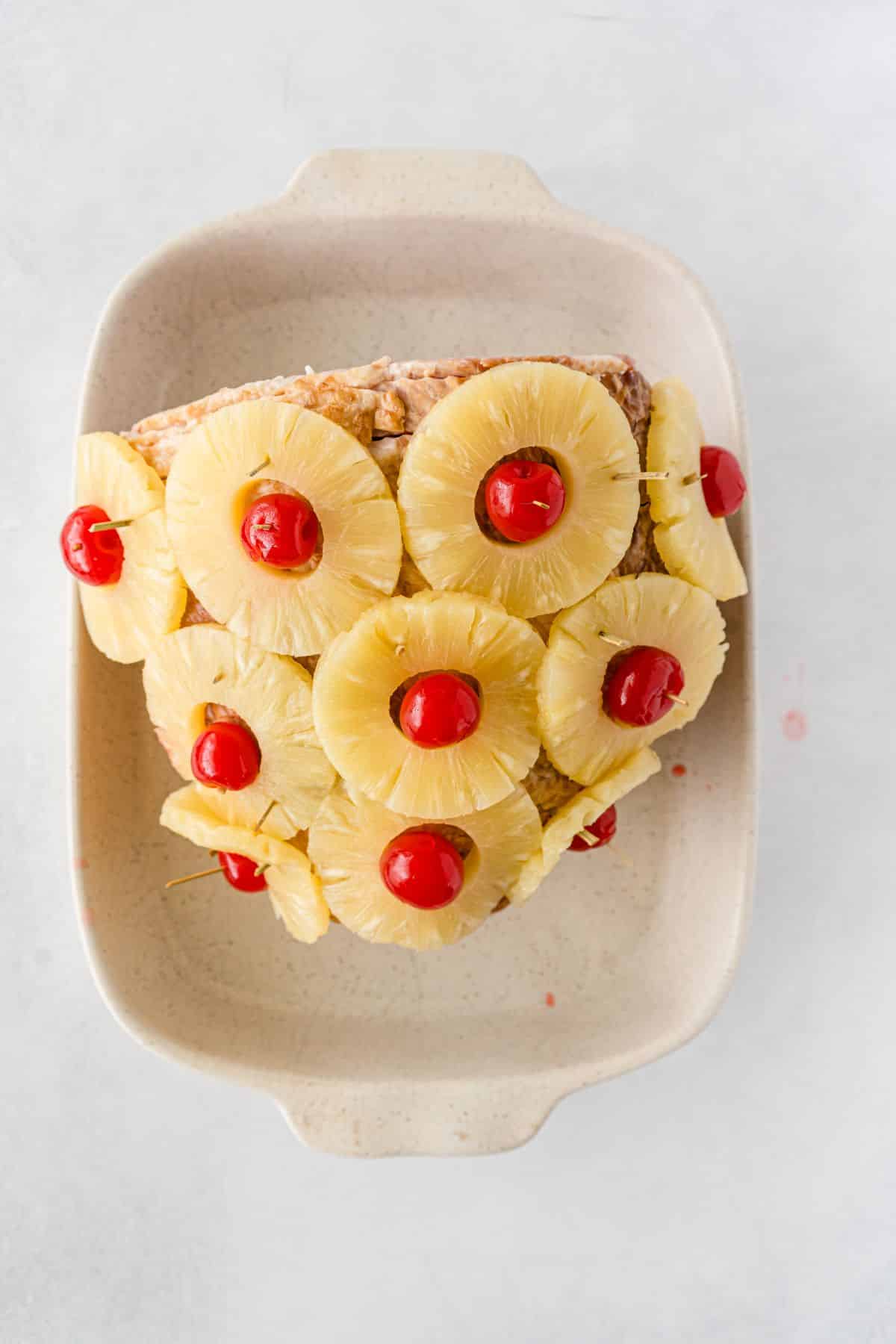 Ham with cherries and pineapples  in a baking dish.
