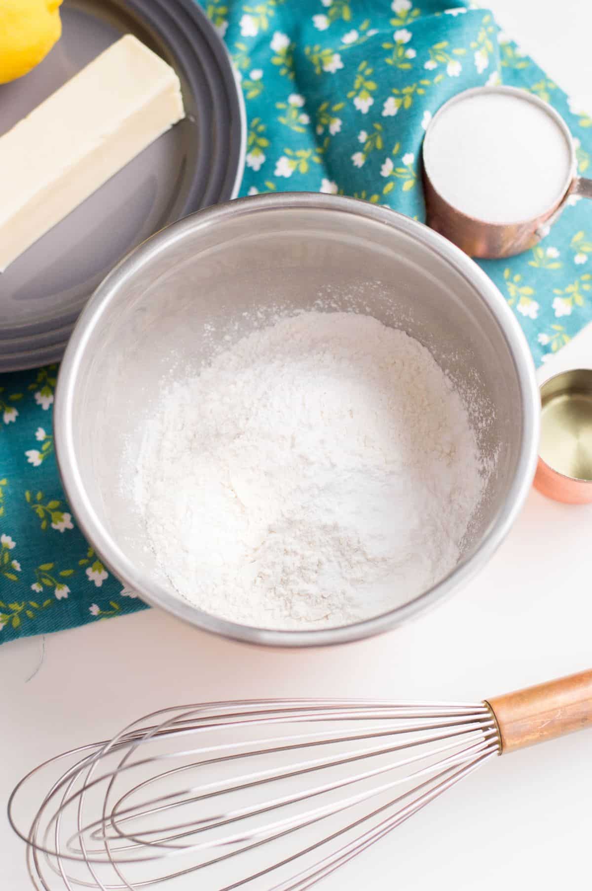 Flour, baking powder and salt in a  bowl. Other ingredients and wire whisk on the side.