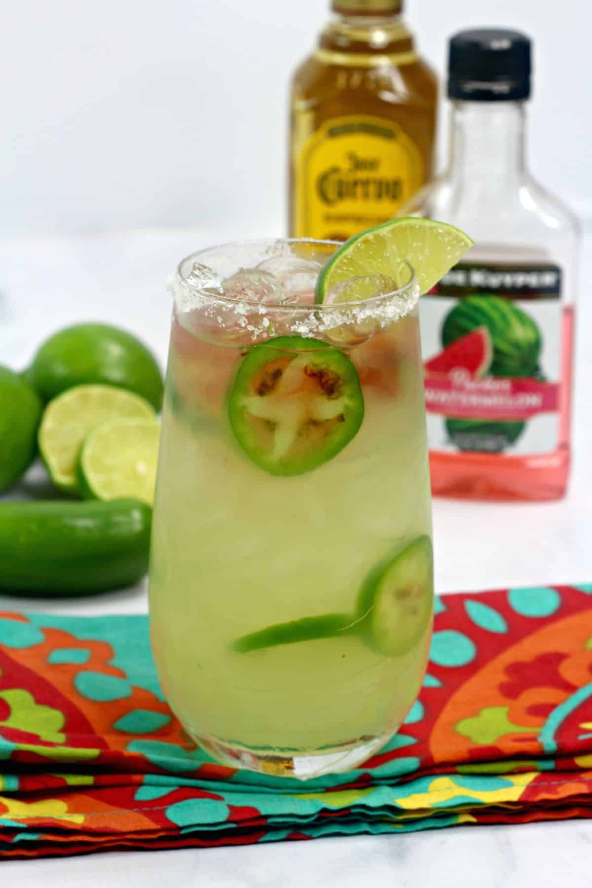 Texas Margarita in a rimmed glass, garnished with jalapenos and lime.