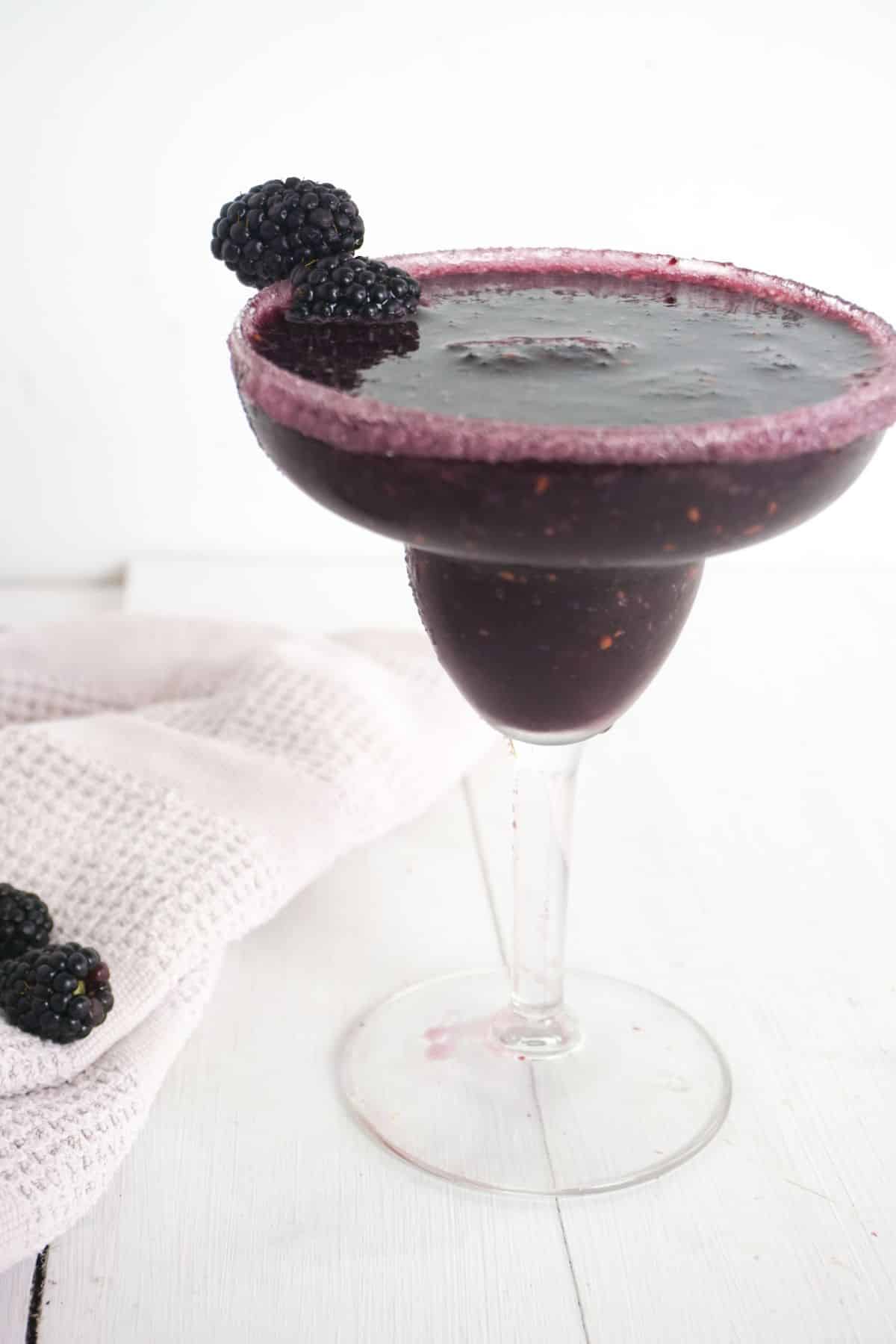 Blackberry Margarita in a serving glass with blackberries on the side.