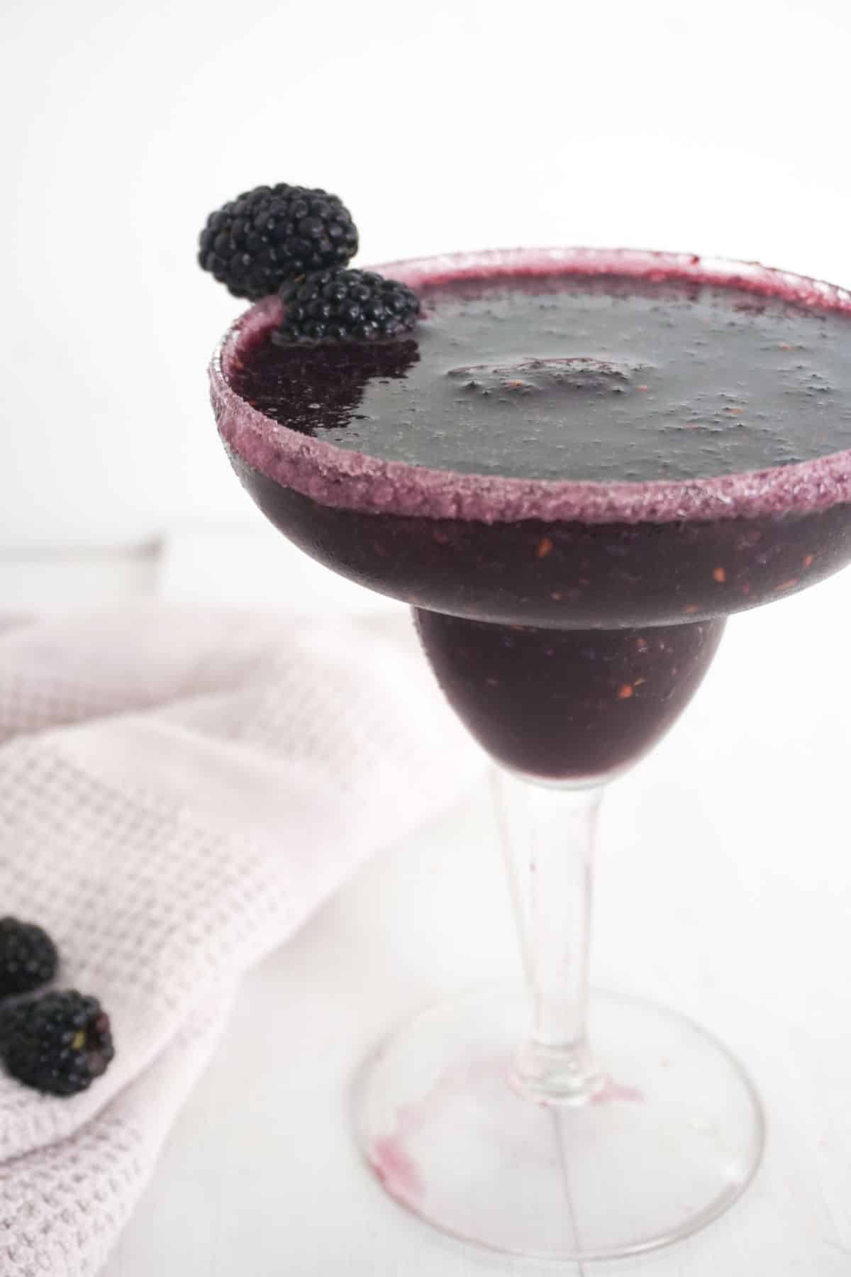 Blackberry Margarita in a serving glass with blackberries on the side.