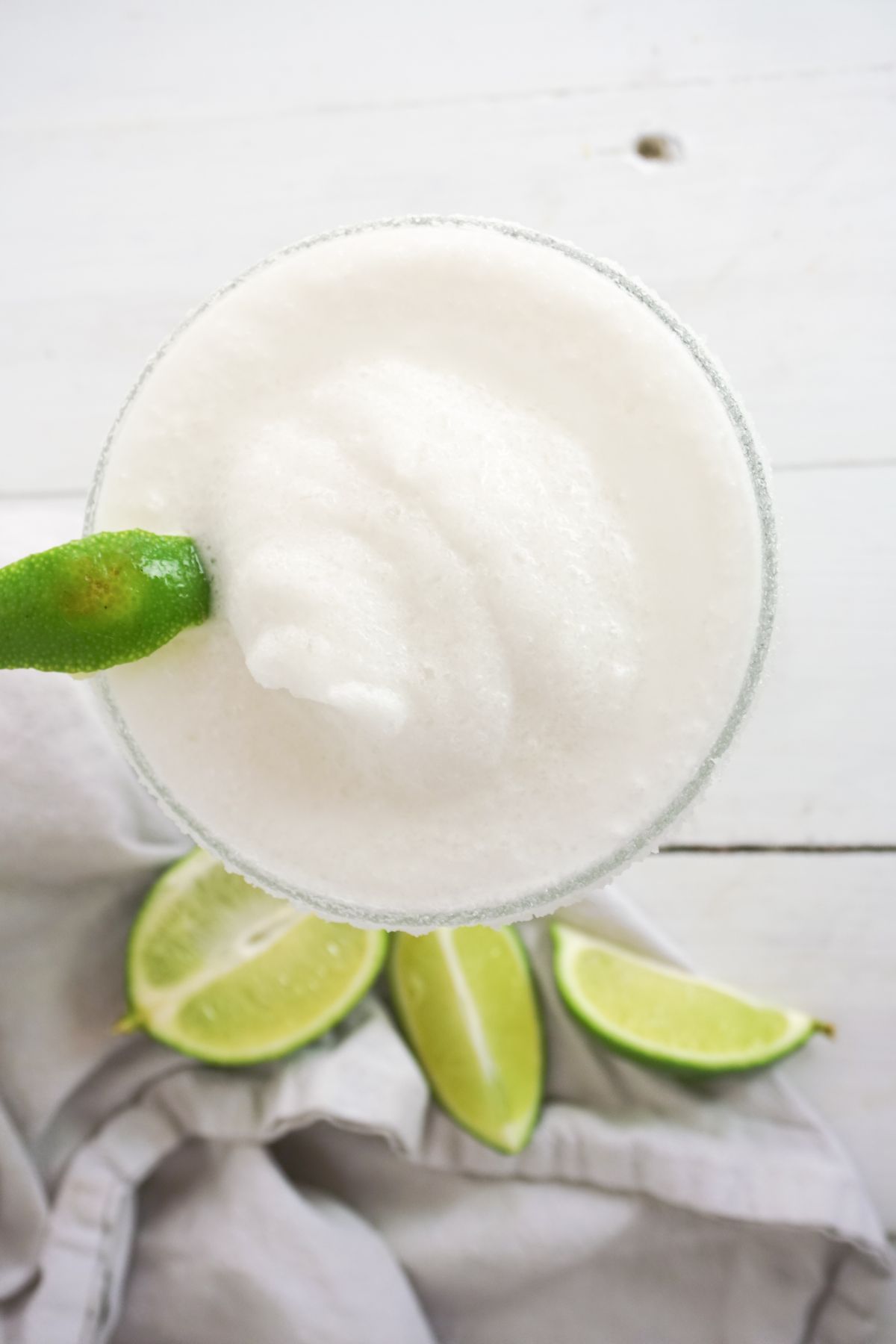 overhead view of a Coconut Lime Margarita in a serving glass, garnished with lime.