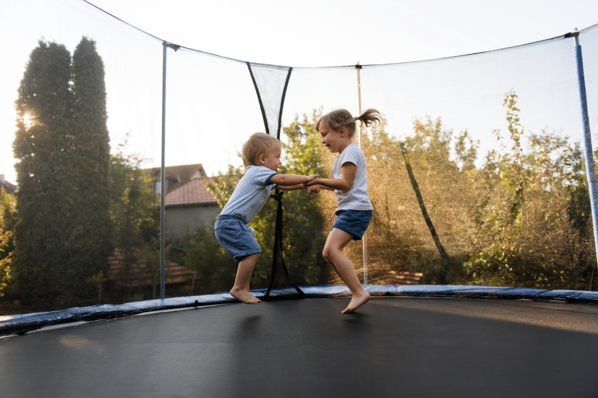 kids jumping on a trampoline while holding hands.