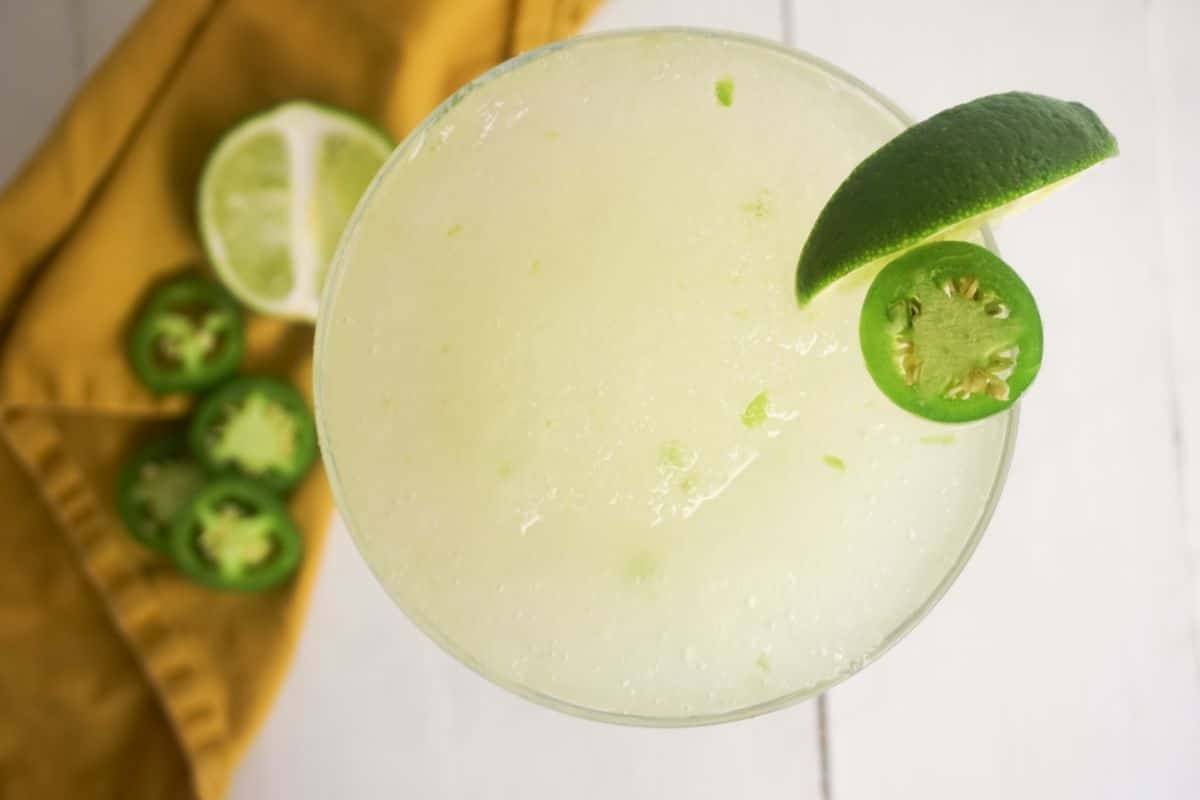 Spicy Skinny Margarita in a serving glass, garnished with lime and jalapeno on the side.