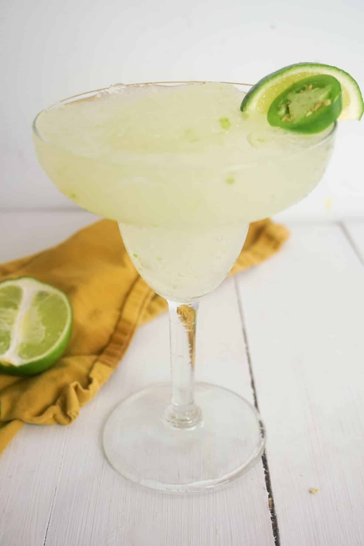 Spicy Skinny Margarita in a serving glass, garnished with lime and jalapeno on the side.