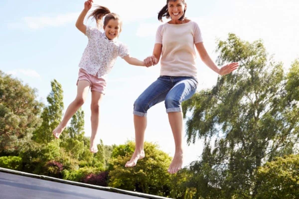 mom and daughter jumping on a trampoline.