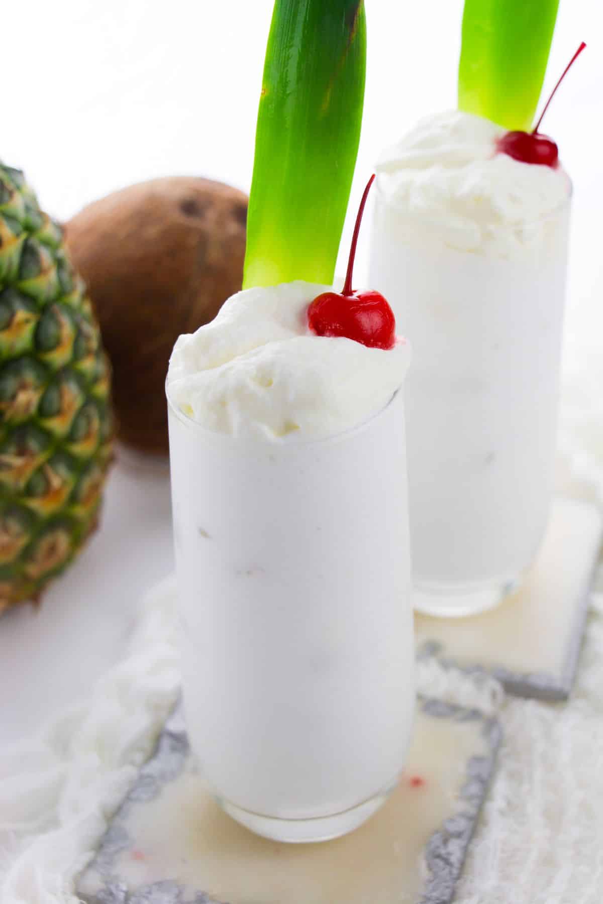 Pina Colada Recipe With Coconut Milk in a glass, topped with whipped cream and a cherry.