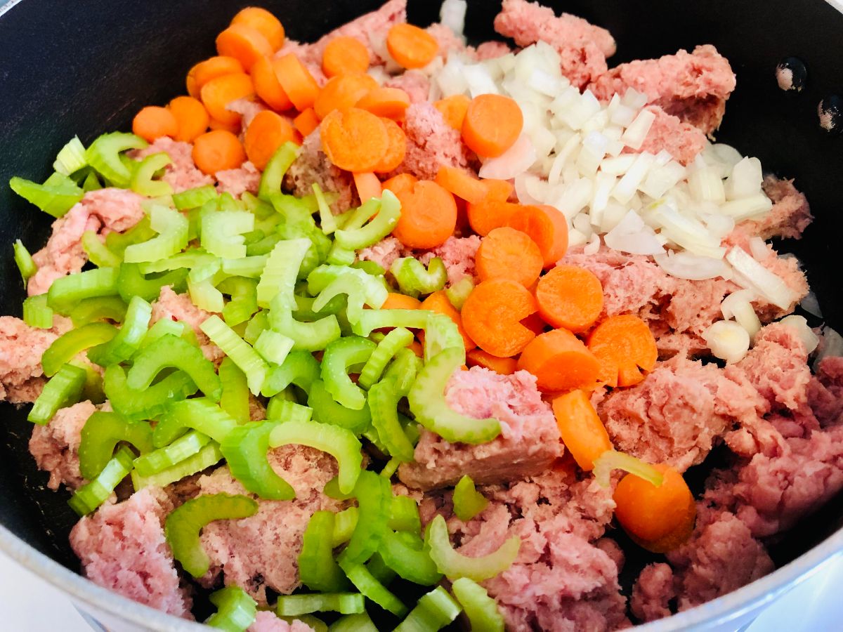 Ground meat, onion, celery, and carrots in a skillet.