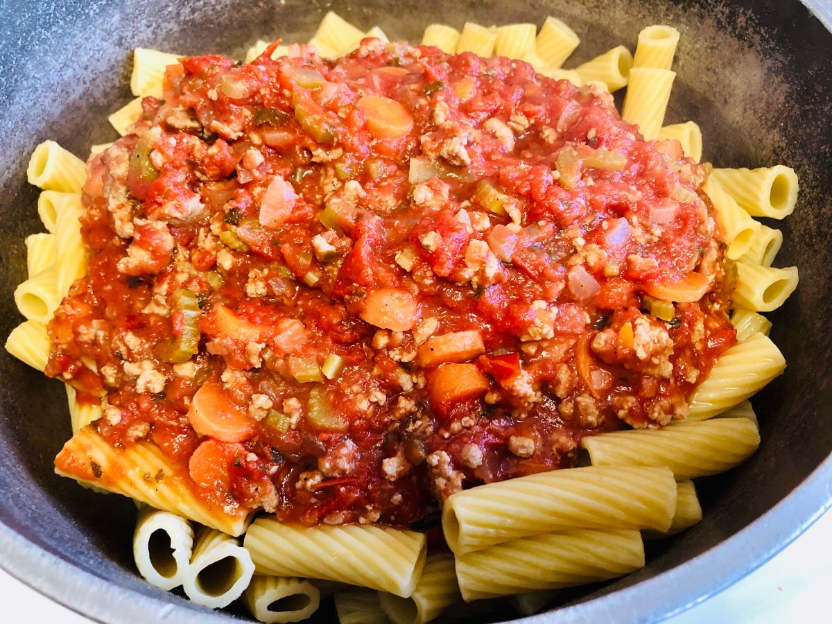 Cooked pasta and meat sauce in a mixing bowl.