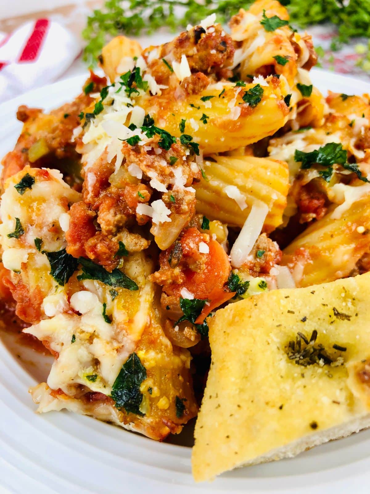Baked Rigatoni with Meat Sauce on a serving plate with garlic bread on the side.