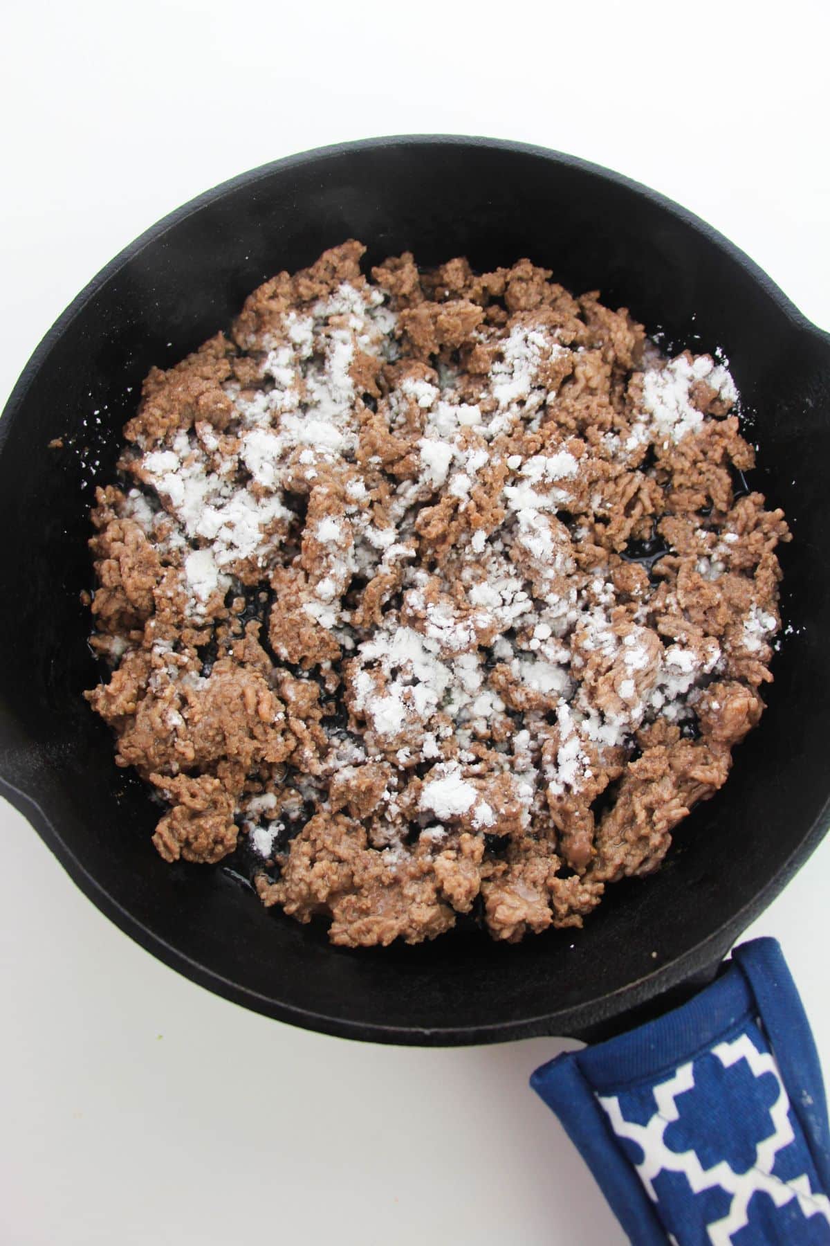 Cornstarch is added to the beef in a skillet.