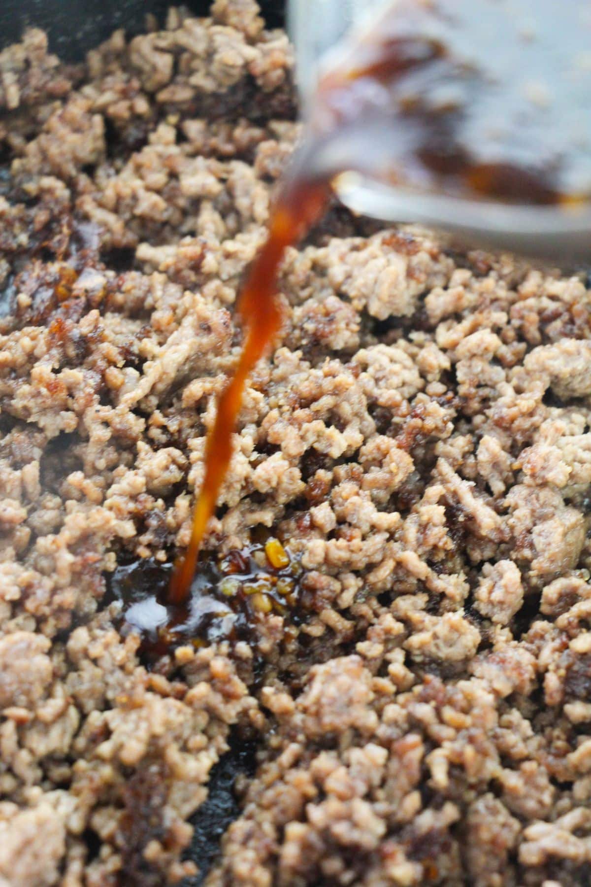 A sauce mixture is being poured in the beef.