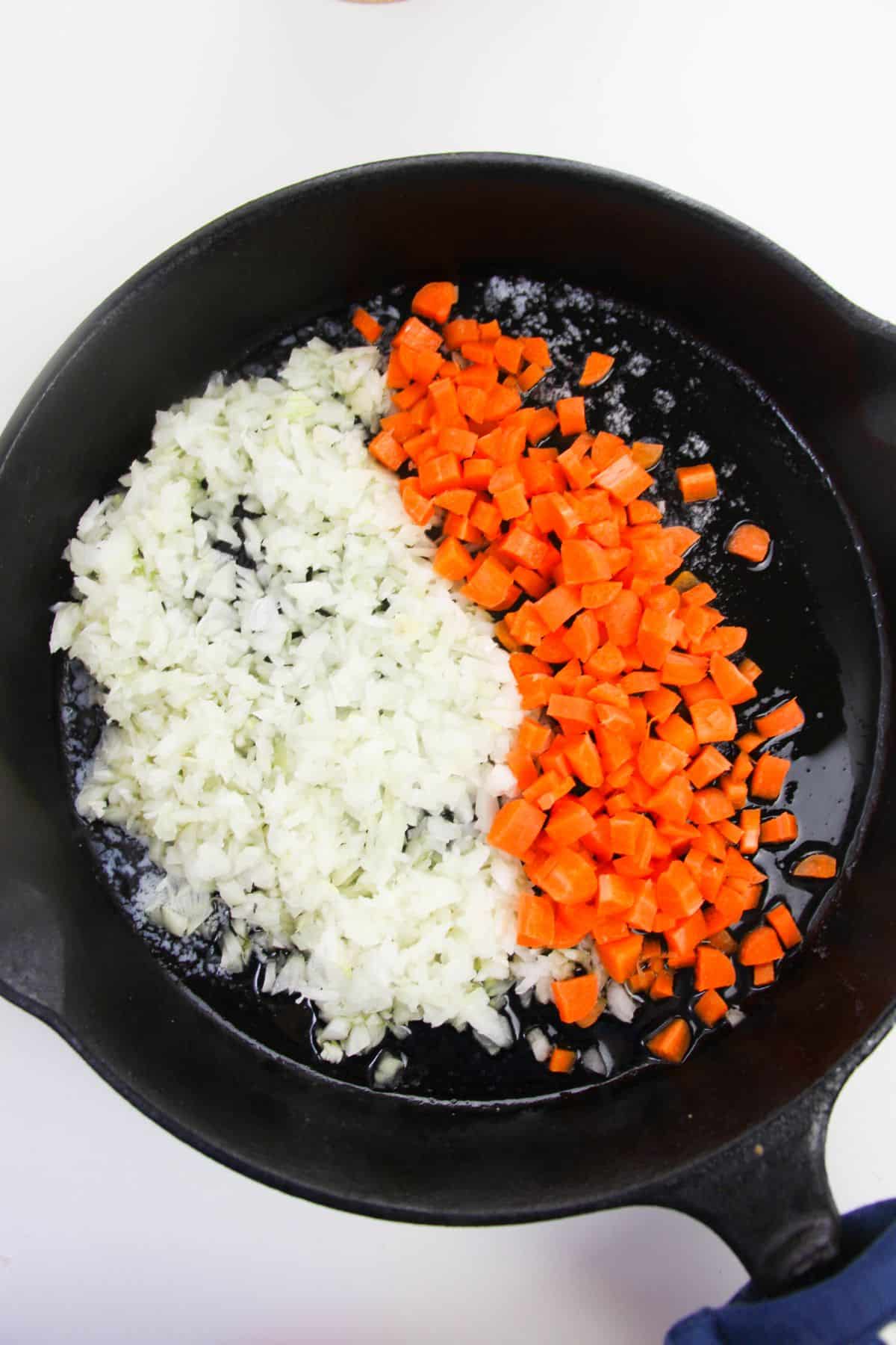 Onion and carrots in a skillet.