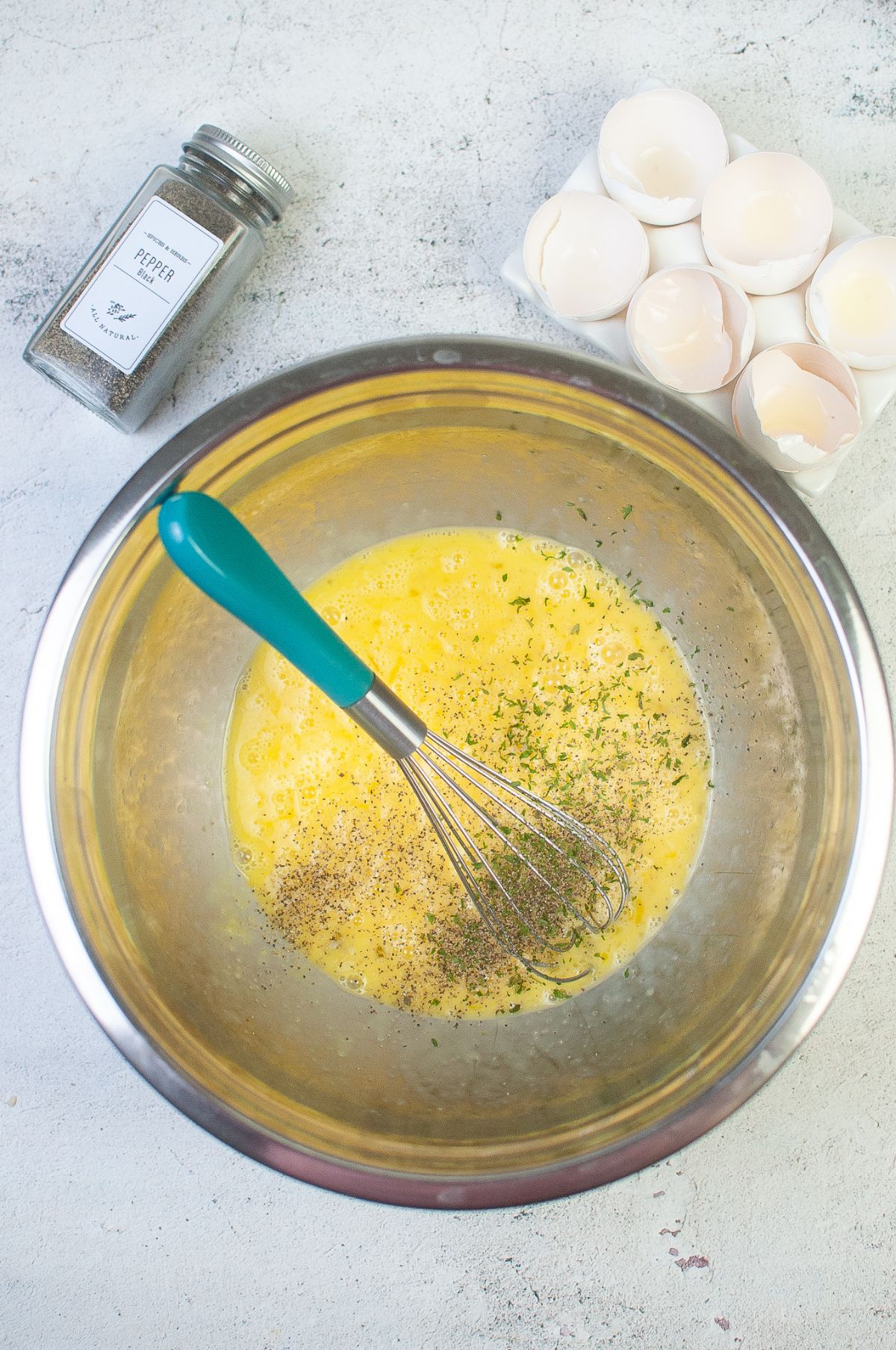 Egg and seasoning in a mixing bowl with whisk.