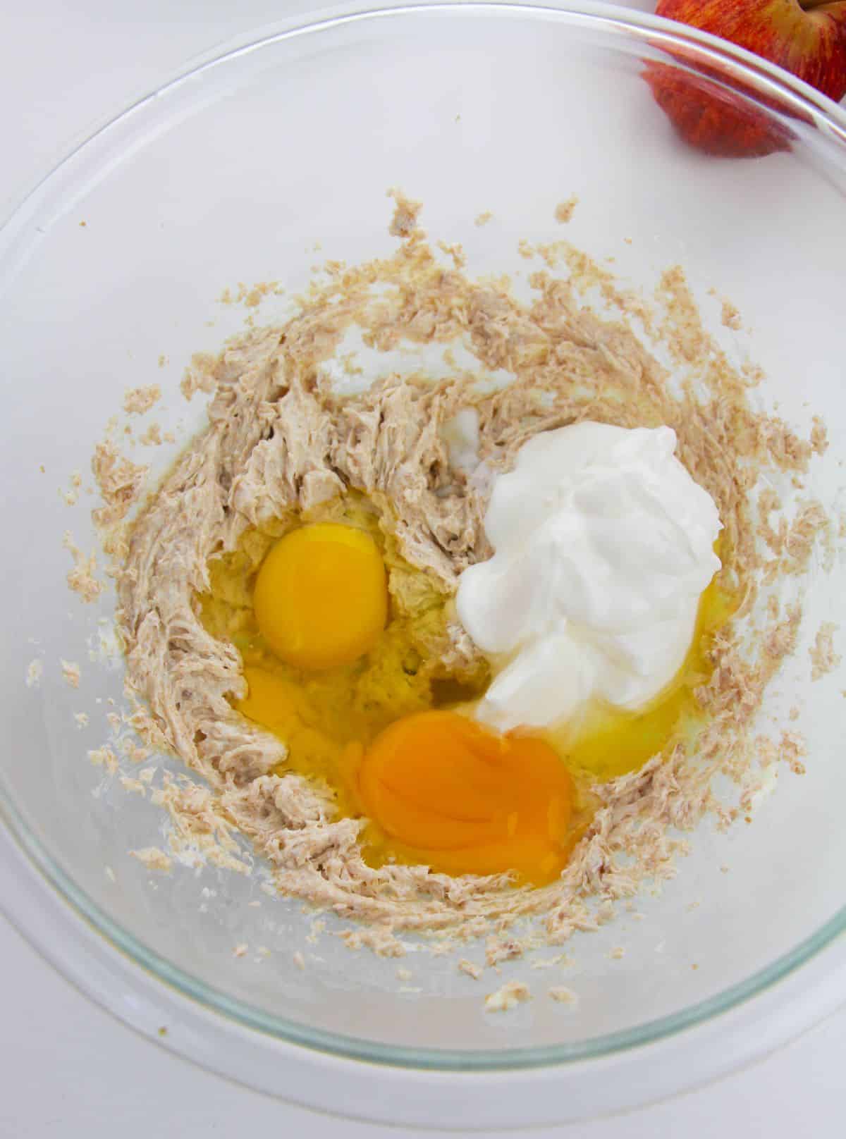 Eggs and Greek yogurt are added to the mixture in a mixing bowl.