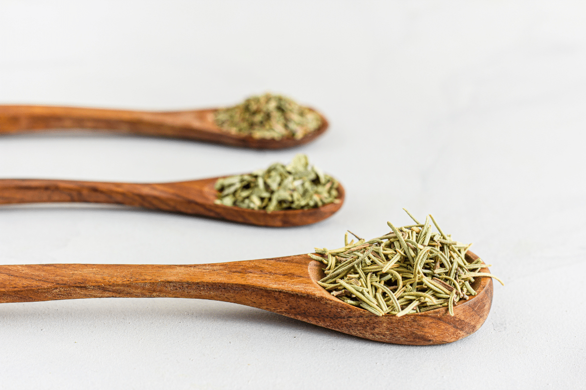 Italian seasoning and herbs on wooden spoons.