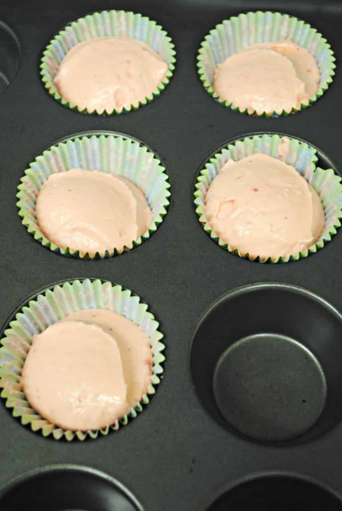 Cupcake pan with liners filled with cake mixture.
