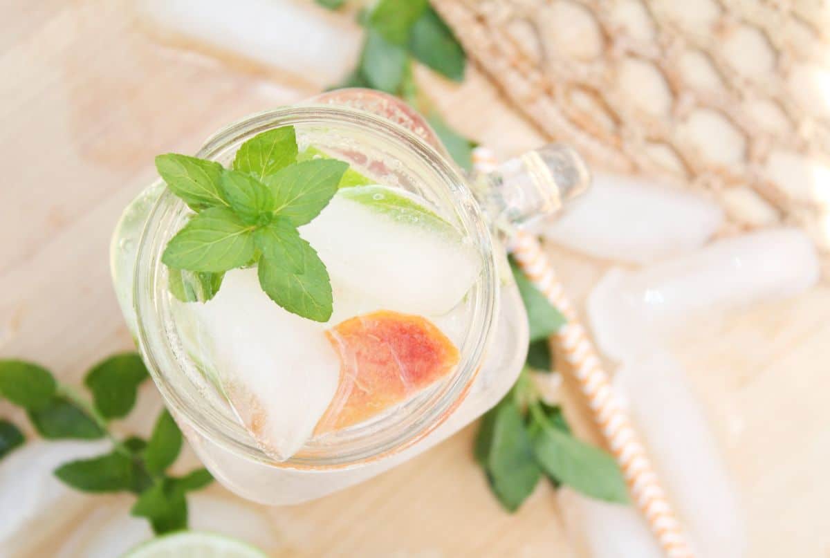 Close-up view of Peach Mojitos in a glass jar garnished with mint leaves.