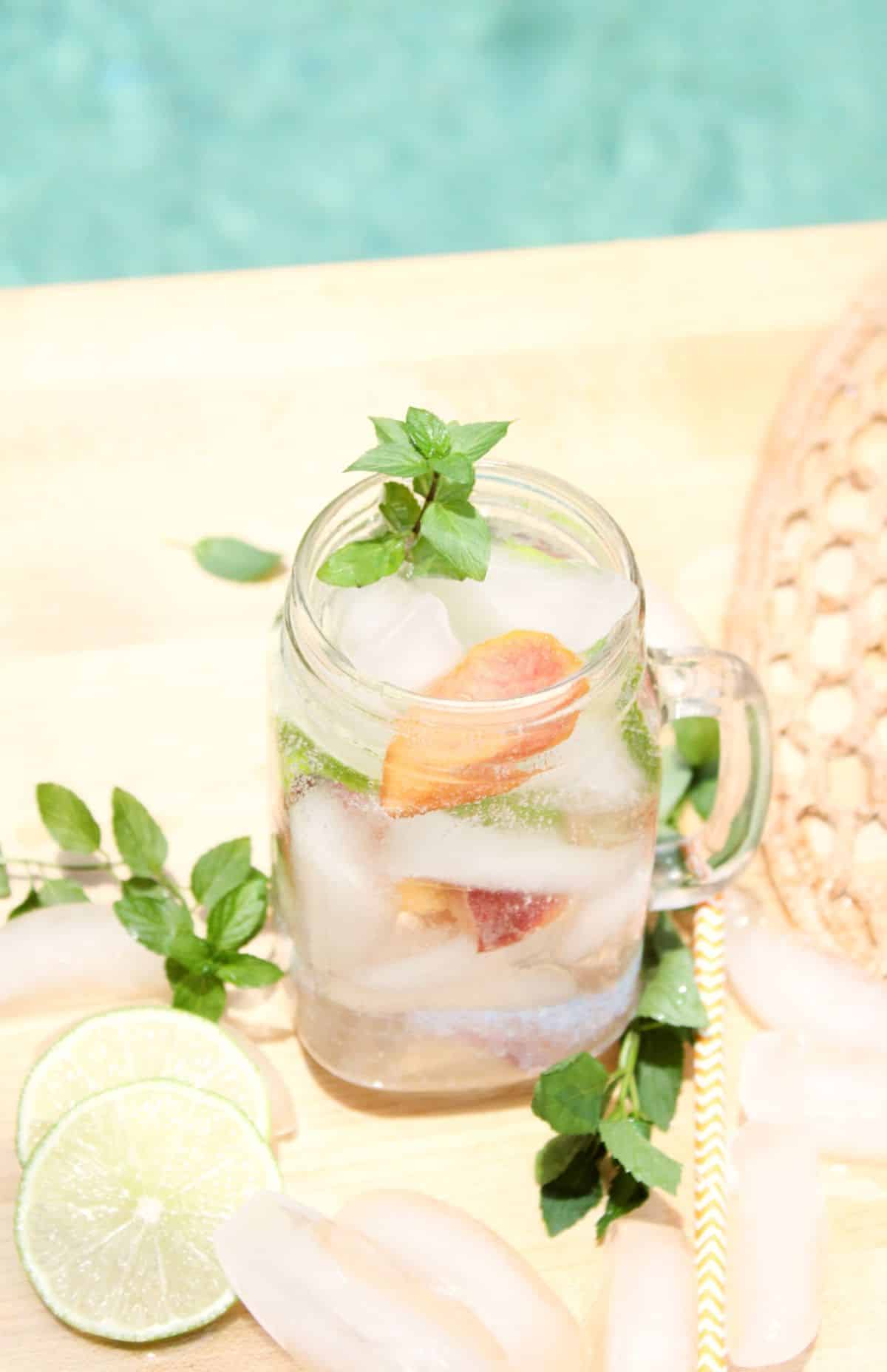 Peach Mojitos in a glass jar garnished with mint leaves.