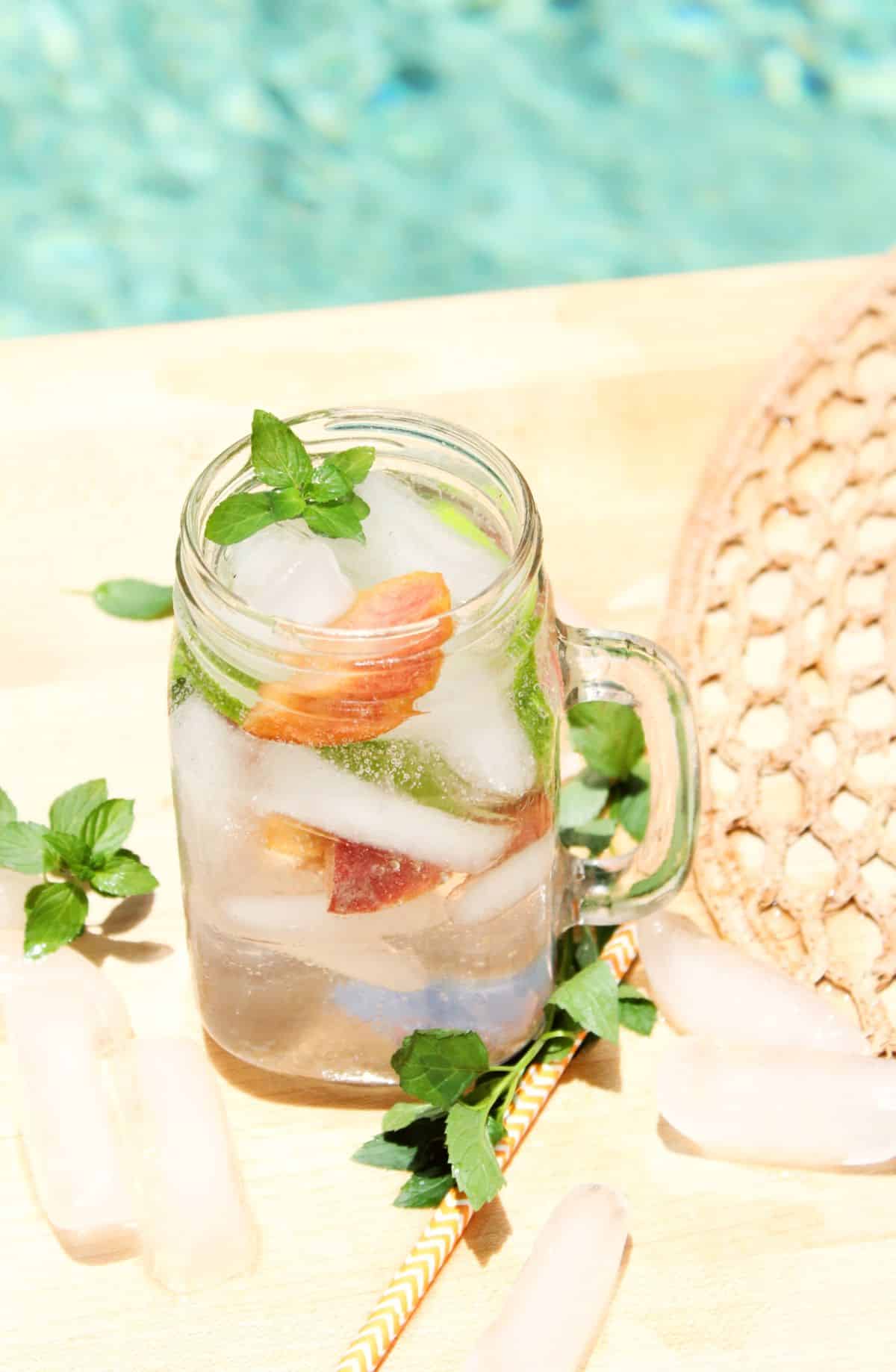 Peach Mojitos in a glass jar garnished with mint leaves.