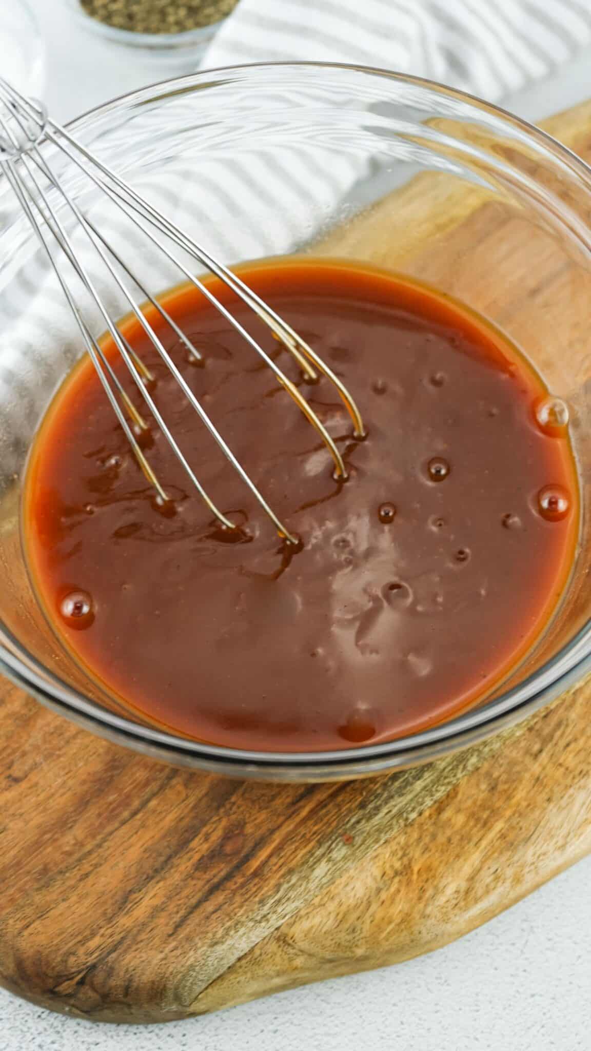 Sauce for glazing in a mixing bowl with whisk in it.