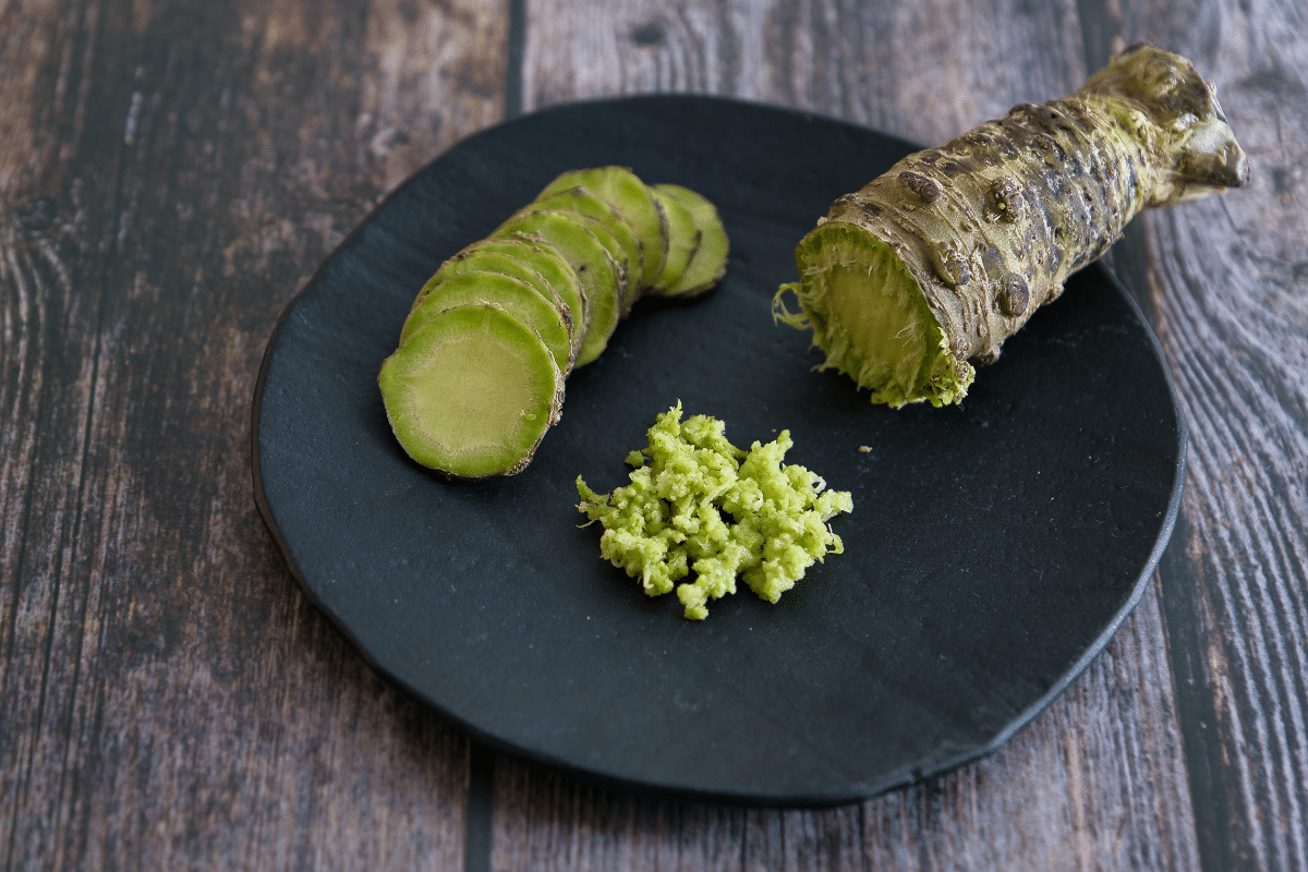 Fresh and grated Japanese wasabi on a black plate.