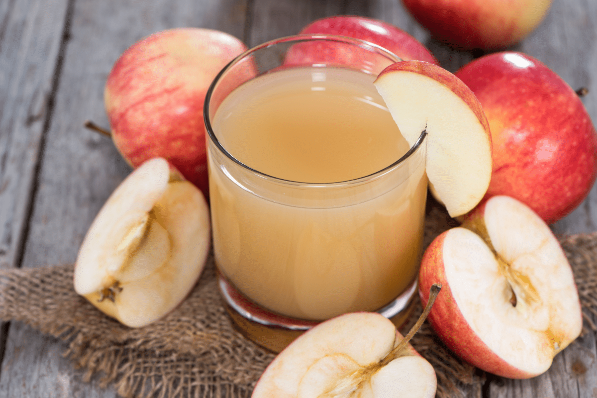 Apple juice in a glass with fresh apples on the side.