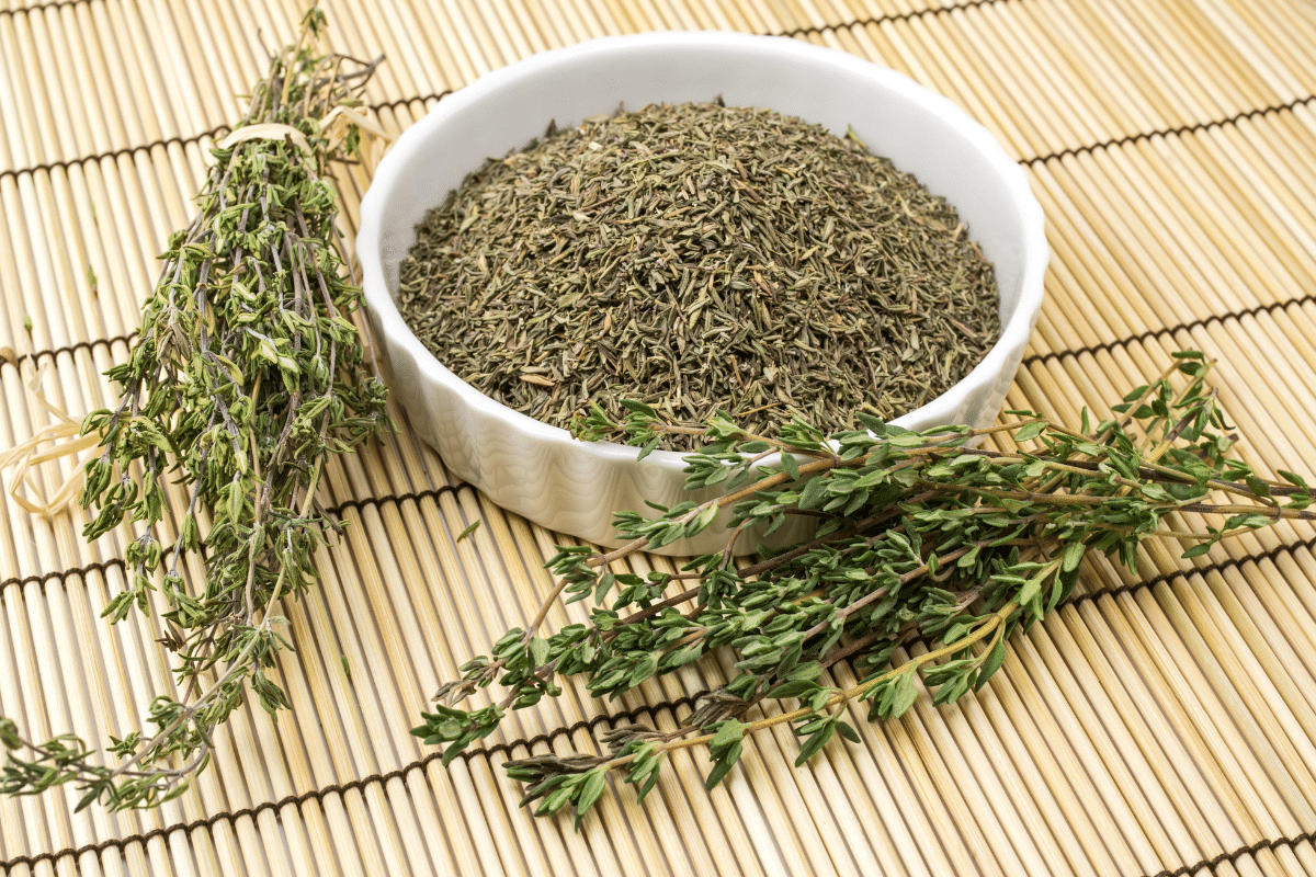 A bowl of dried thyme, with fresh and dried thyme on the side.